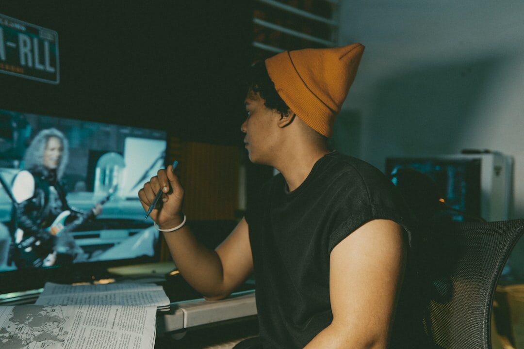 Young man editing video footage on multiple monitors in a bright studio