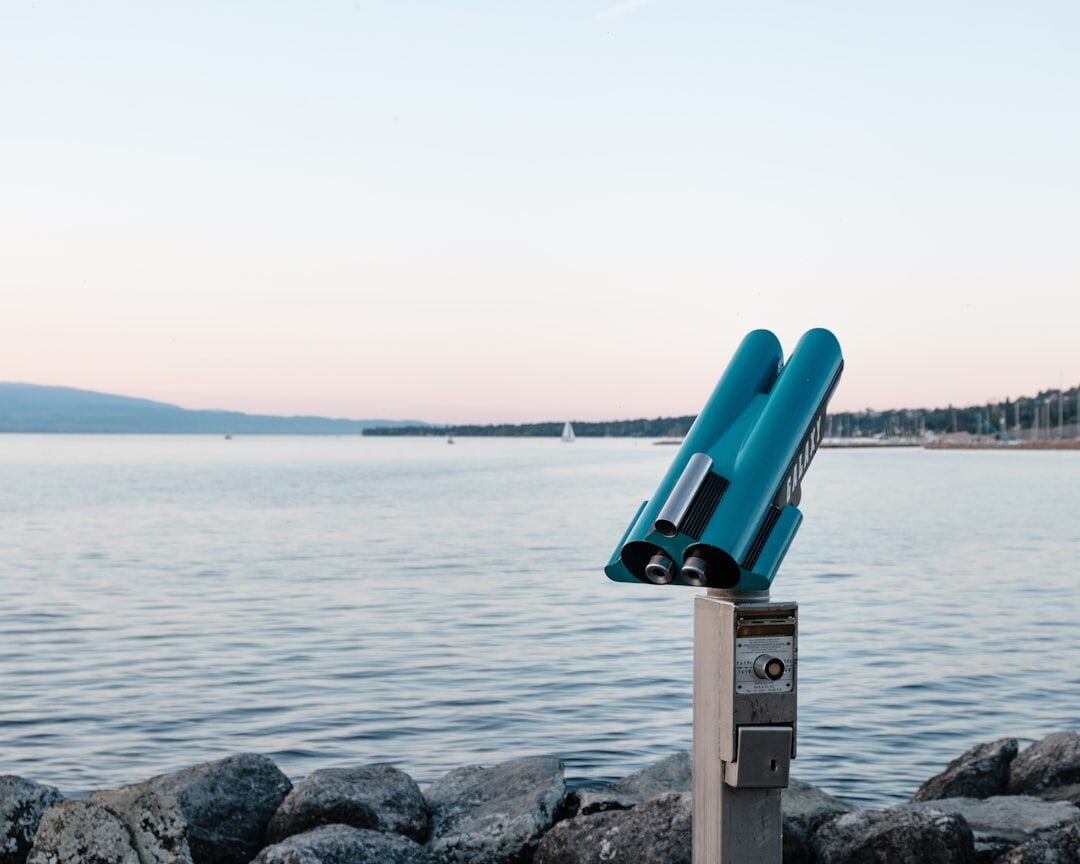 Video camera and tripod set up on the shore of Lake Geneva at sunset